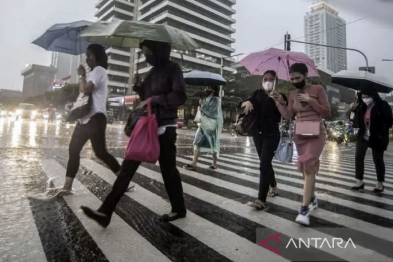 Sejumlah karyawati menyeberangi jalan yang tergenang air di depan gedung perkantoran saat hujan ringan. (ANTARA/Muhammad Adimaja/am.)
